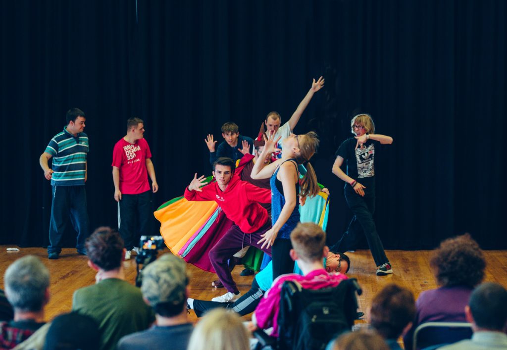 Young people performing in front of an audience, moving and dancing.